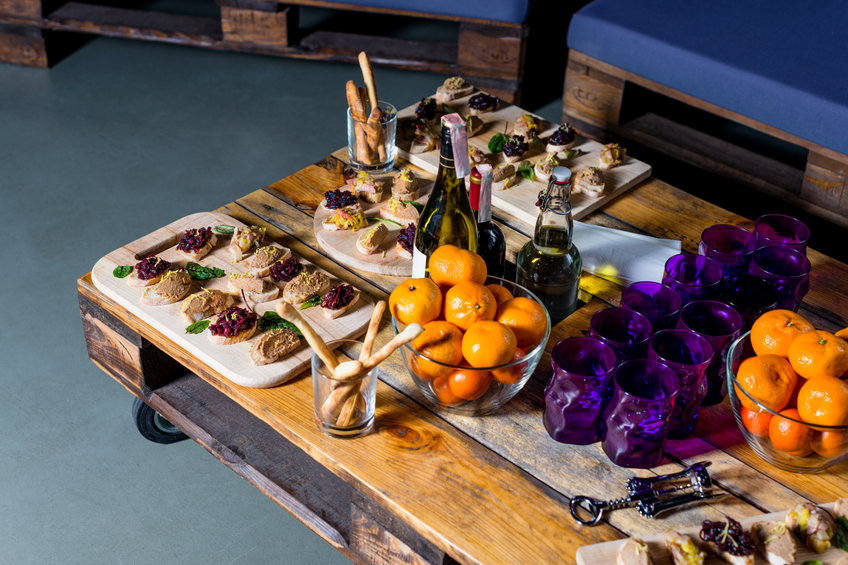 Wooden tray of appetizers on pallet coffee table at banquet.